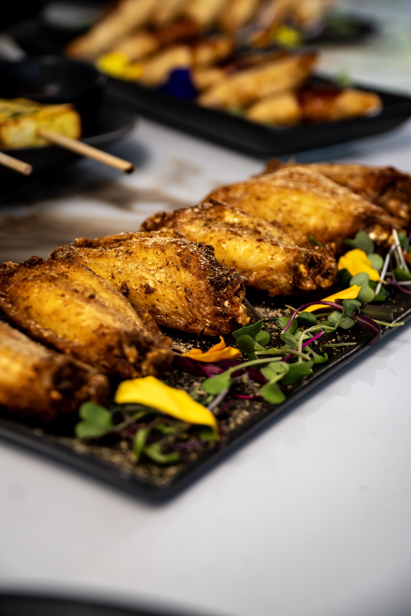 Spiced fried wings with microgreens and edible flowers